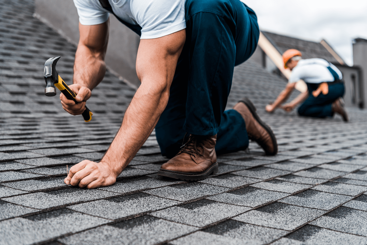 two roofers are laying new shingles on a roof