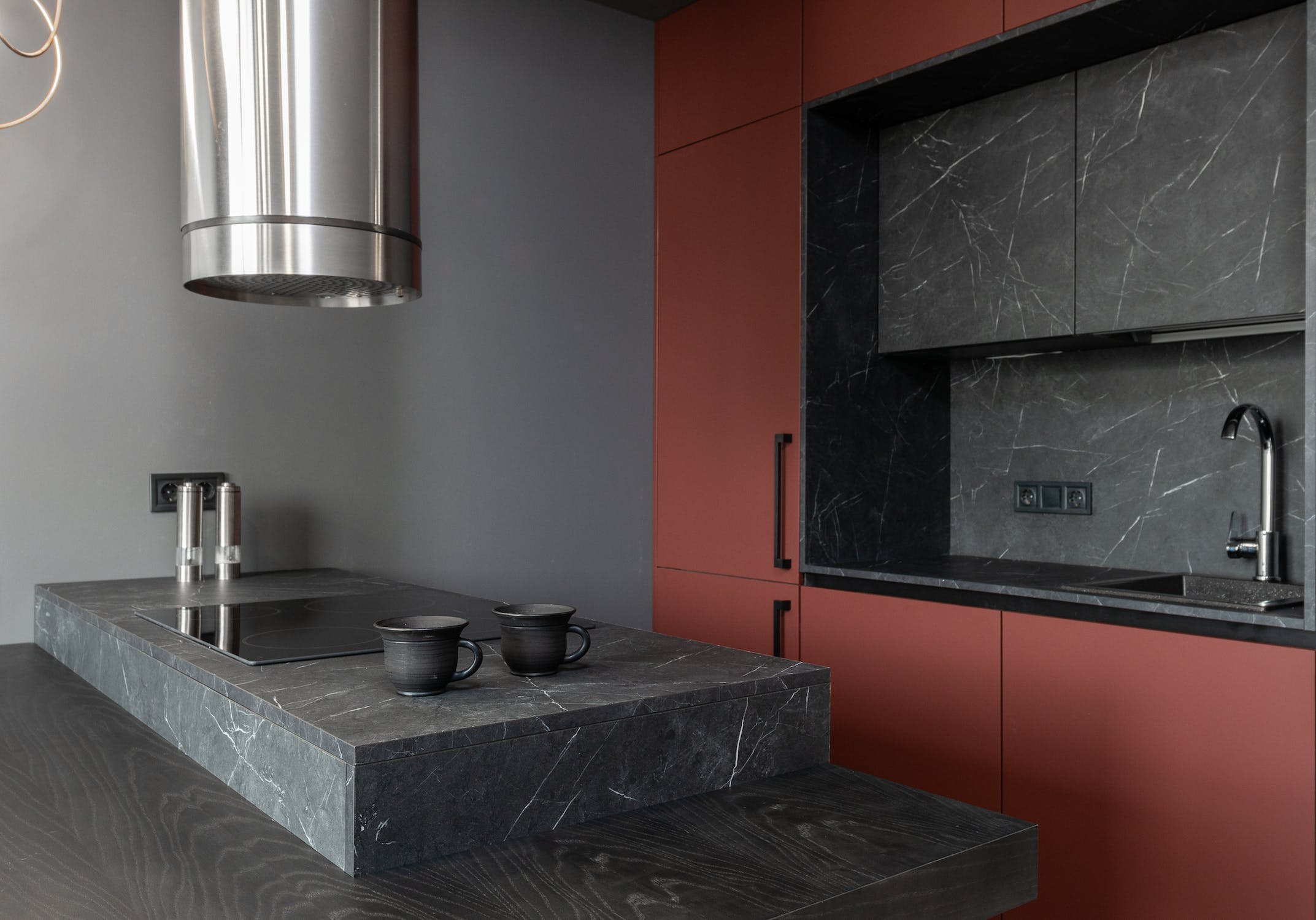 dark red and black modern kitchen with black taps and red cabinetry