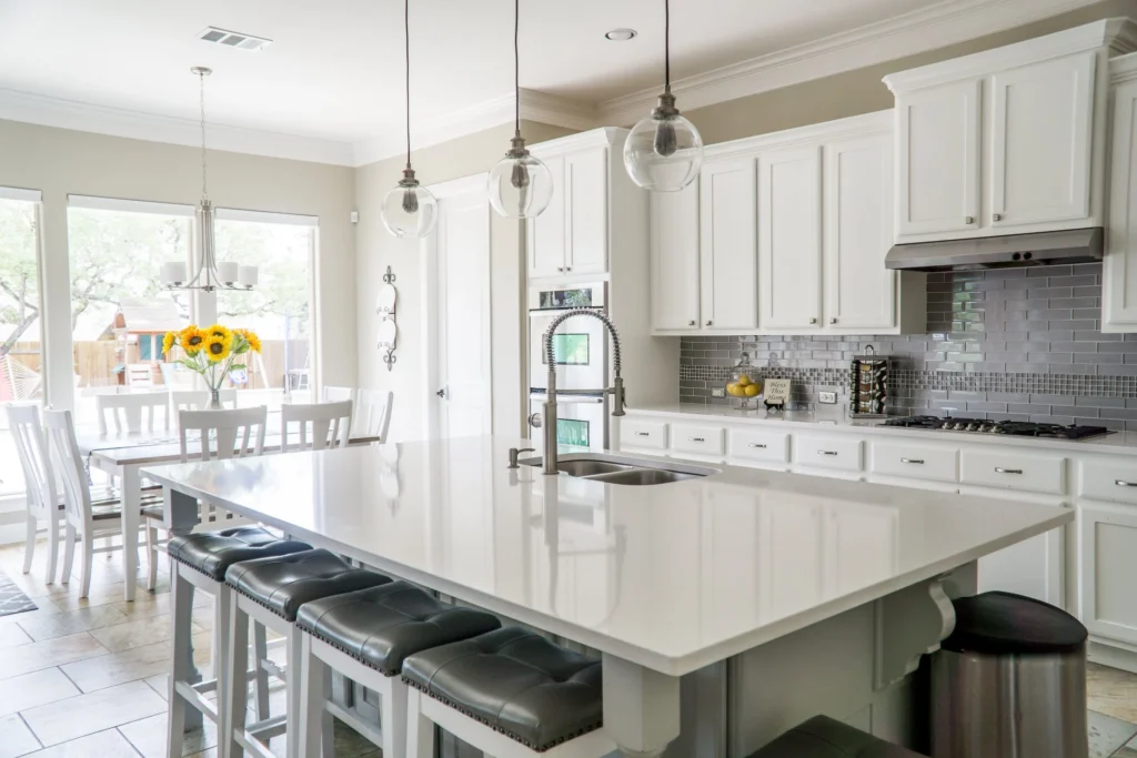 a kitchen with a large center island, bar stools, and white cabinets