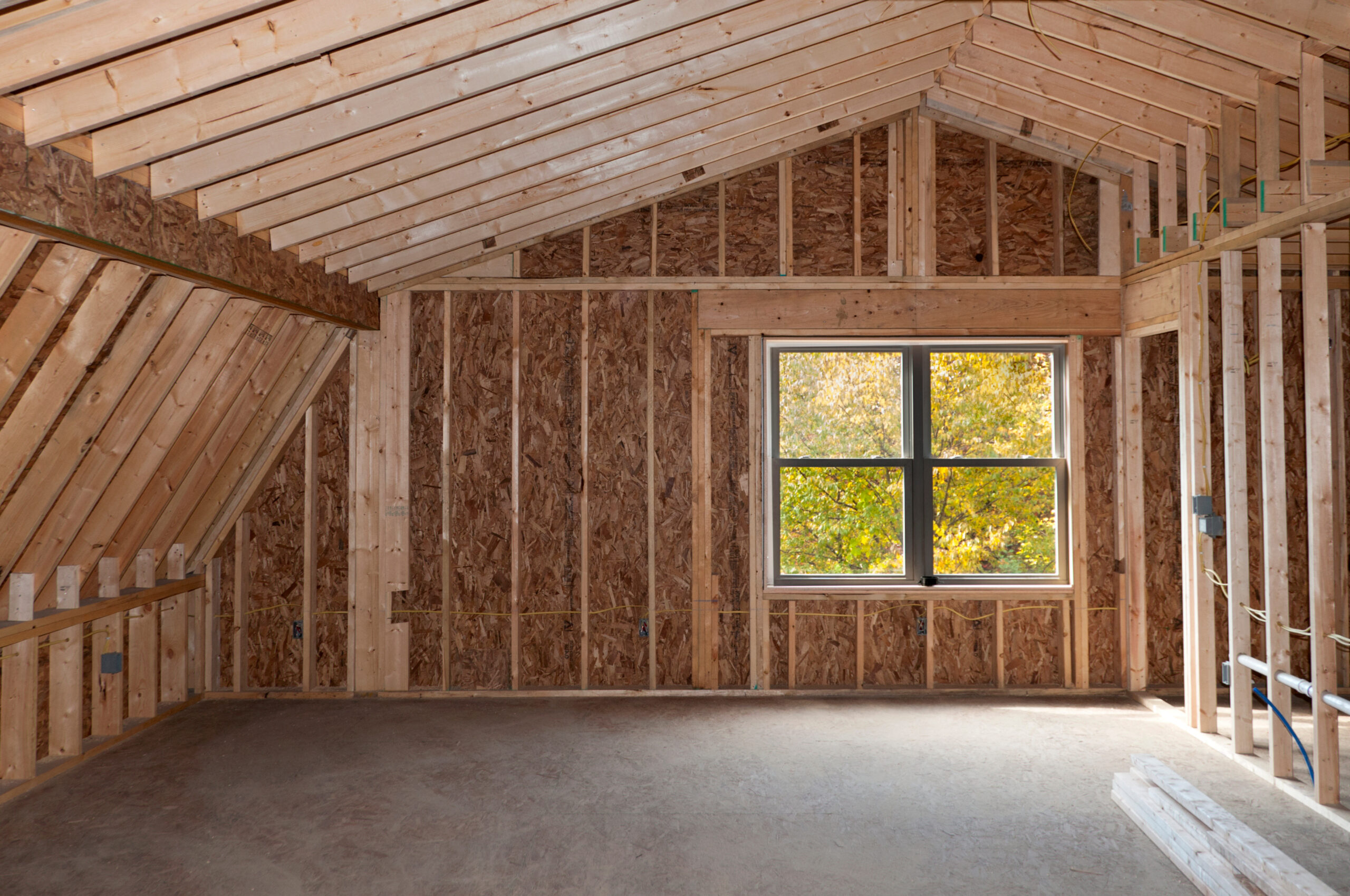 Room addition construction with pitched ceiling and autumn trees view window
