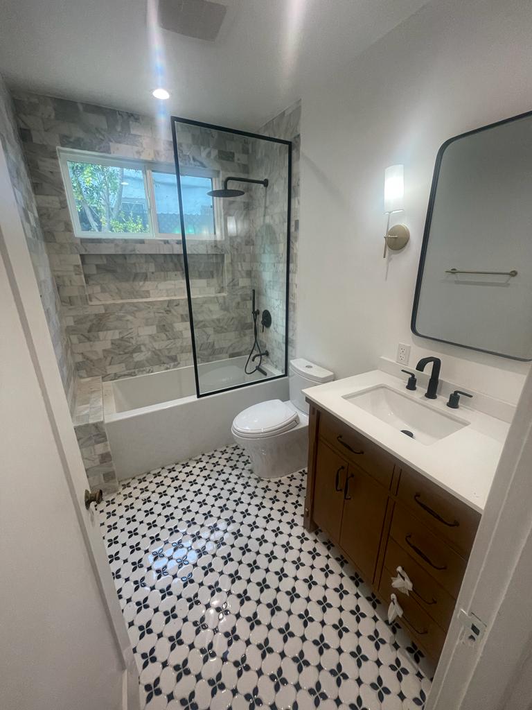 a small bathroom with tile floors, sink vanity and bathtub