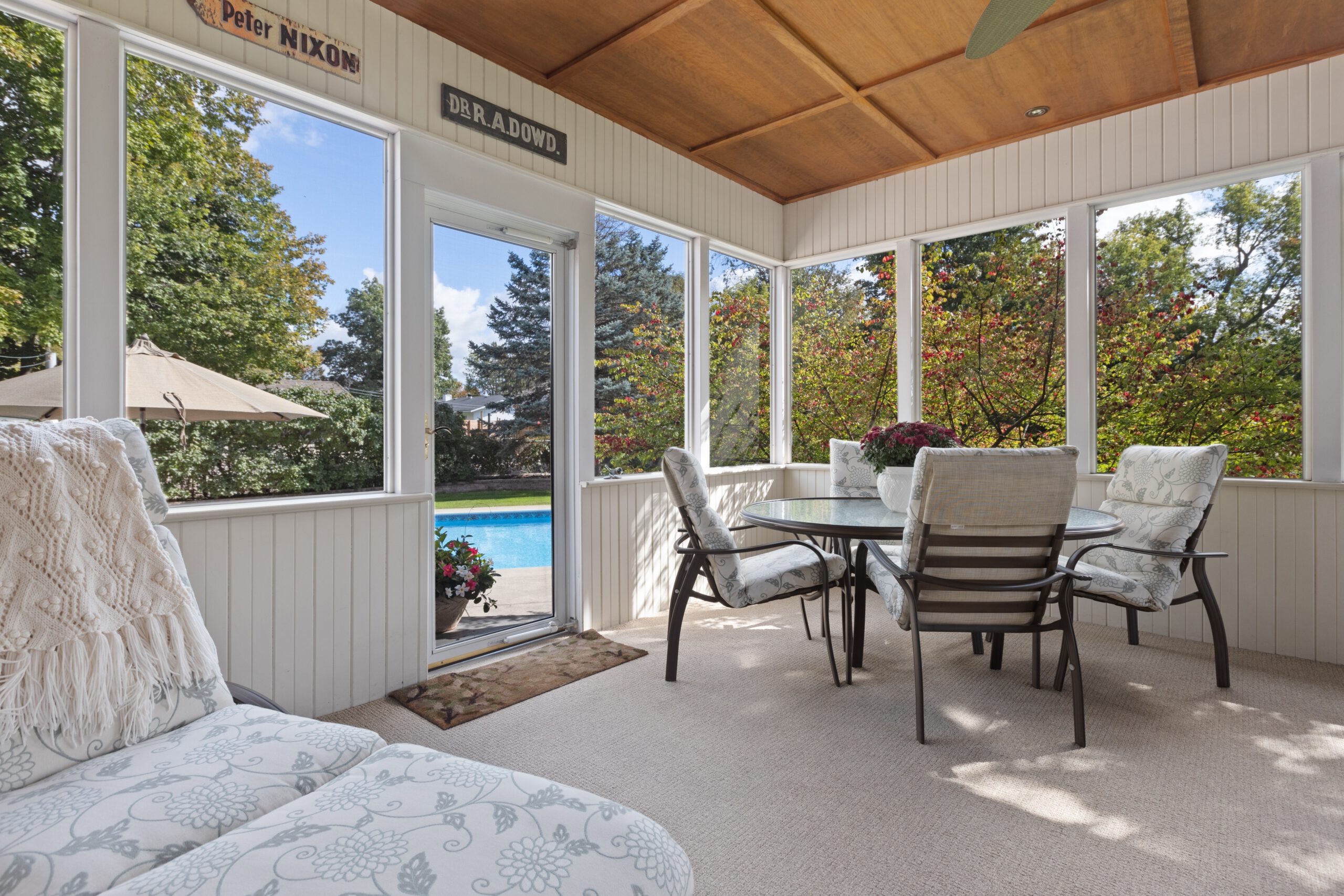 an outdoor patio area with furniture, a pool, and a screened-in porch, in the style of light brown and white colors